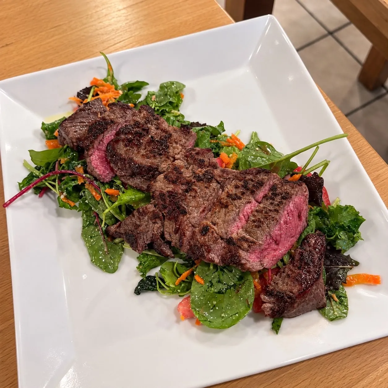 Bœuf grillé tranché sur lit de jeunes pousses et carottes